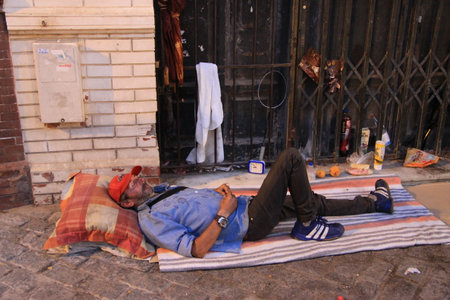 An unknown homeless man sleeps on a street in the city of Sevilleのeditorial素材