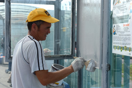 A guest worker paints a metal structure on one of the streets of Moscowのeditorial素材