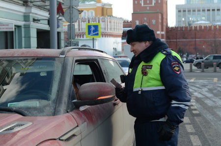 The inspector of the road patrol service of the police checks the documents of the driver of a stopped car in the center of Moscowのeditorial素材