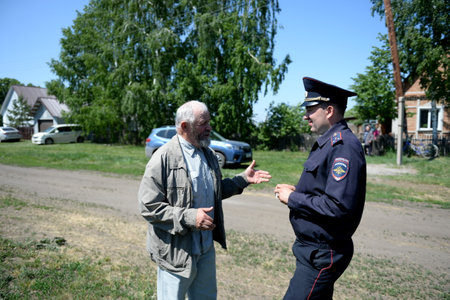 A local police commissioner talks with an elderly man on the street of the village of Poteryaevka in the Altai Territoryのeditorial素材