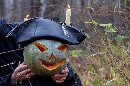 Stranger with covered face keeps pumpkin on his hands in the forestの写真素材