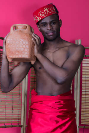 Black man posing near a reed screen on a red backgroundの写真素材