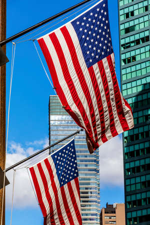 Two bright american flags and the skyscrappers in a sunny weatherの写真素材