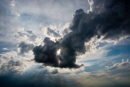 The sun\'s rays streaming through the big black storm cloud. 