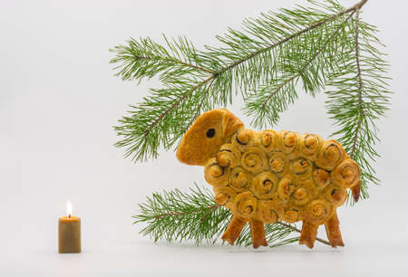 Pastries Sheep with a green pine branch and a burning candle.の写真素材
