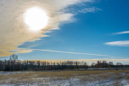 Winter landscape with the sun bursting through a large cloud.の写真素材