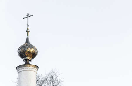 Golden Church steeple with a cross on the white background of the sky.の写真素材