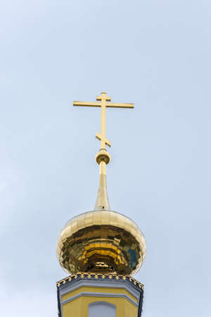Golden Church steeple with a cross on a blue sky background.の写真素材