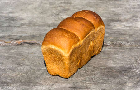 Golden loaf of wheat bread on a gray background.