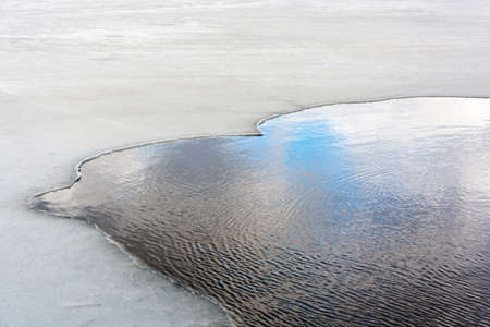 Turbulent open water framed by thin ice.の写真素材