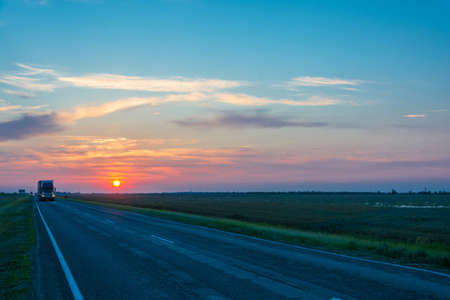 Beautiful red sunset. In the foreground the road with cars.の写真素材