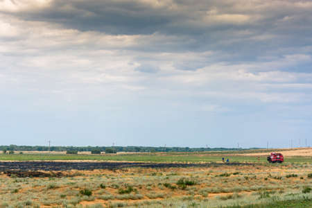 Firefighters extinguished the burning grass in the desert. Black spot stands out on yellow-green background.の写真素材