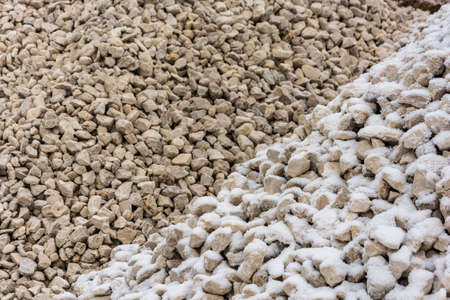 The texture of gravel, covered with a thin layer of white snow.