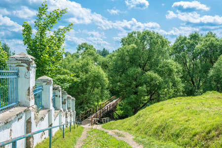Path leading down to a wooden bridge along the old stone wall in a Sunny summer day. Shuya, Ivanovo...