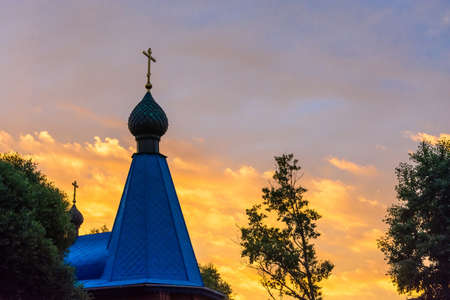 Church domes with crosses on the background of fabulously bright orange-yellow sky.の写真素材