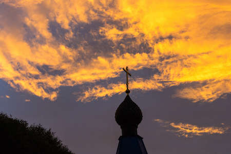 Church domes with crosses on the background of fabulously bright orange-yellow sky.の写真素材
