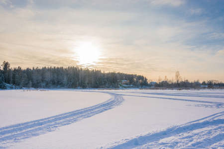 Beautiful frosty winter evening on snow-covered river in back light.の写真素材