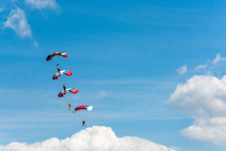 Parachutists descending on the background of beautiful cloudy sky on a Sunny day.のeditorial素材