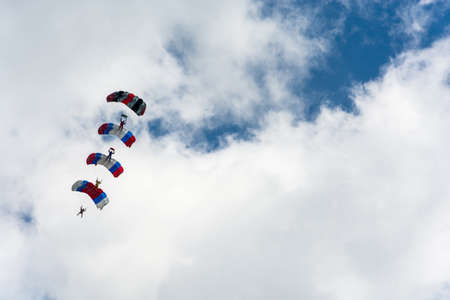 Parachutists descending on the background of beautiful cloudy sky on a Sunny day.のeditorial素材