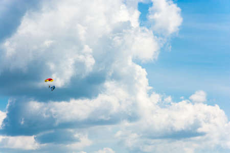Parachutists descending on the background of beautiful cloudy sky on a Sunny day.のeditorial素材