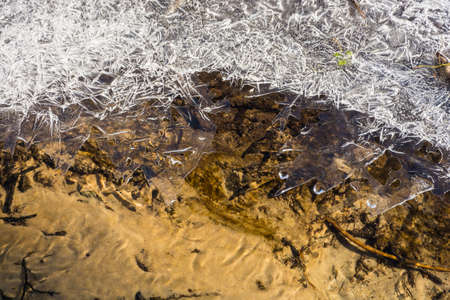 Beautiful texture of thin ice amid the sandy bottom of the Creek.の写真素材