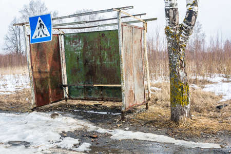 Old curved clock bus stop on the road in March day.の写真素材