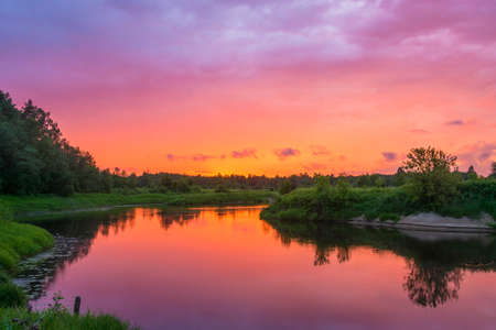 Beautiful orange sunset reflected in the mirrored surface of the river.の写真素材