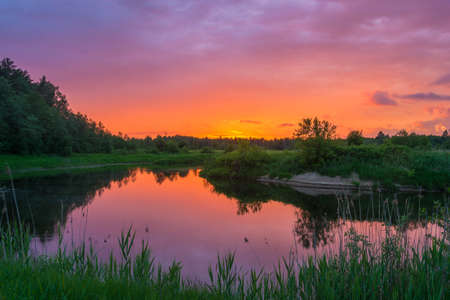 Beautiful orange sunset reflected in the mirrored surface of the river.の写真素材