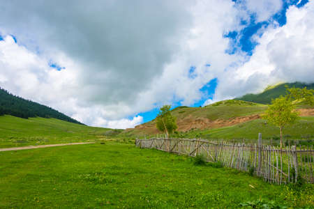 Mountain landscape with wooden fence on a Sunny summer day, Kyrgyzstan.の写真素材