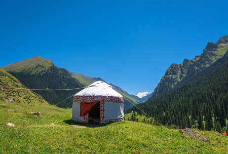 Beautiful mountain landscape with the white Yurt, decorated with a red ornament, Kyrgyzstan.の写真素材