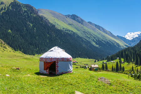 Beautiful mountain landscape with the white Yurt, decorated with a red ornament, Kyrgyzstan.の写真素材