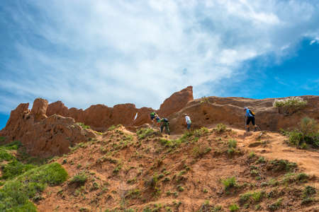 A group of tourists climbs a steep hill in the canyon at Fairy Tale, Kyrgyzstan.の写真素材