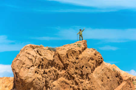 A man stands on a huge rock against the blue sky in the canyon Fairy Tale, Kyrgyzstan.の写真素材