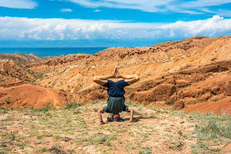 A man performs the asanas in the amazing mountain canyon Tale in summer sunny day, Kyrkyzstan.