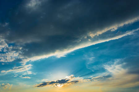 Blue sky with bright clouds, illuminated by the setting sun.