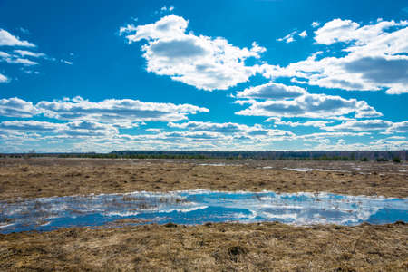 Spring landscape with bright white clouds and the reflections in the water.の写真素材