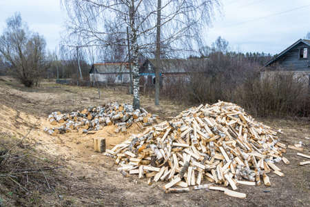 Two large piles of birch firewood in the street in a small village.