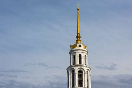 White-stone belfry with a Golden spire against a blue cloudy sky.の写真素材