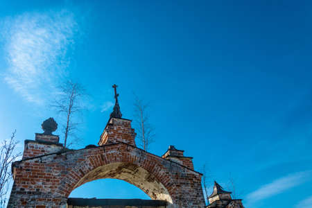 Old Church arch of red brick, overgrown with birches on a background blue sky, Russia.の写真素材