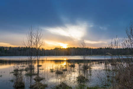 Beautiful orange sunset at the small forest lake in Central Russia.