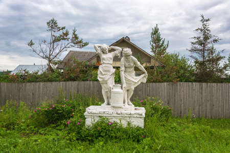 White sculpture of women farmers, bearing a flask of milk among blooming wild rose.の写真素材