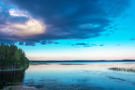 A big black cloud covering the sun, over a lake in Karelia, Russia.の写真素材