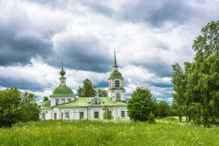 Stone village Church with a green roof in the summer cloudy day.の写真素材