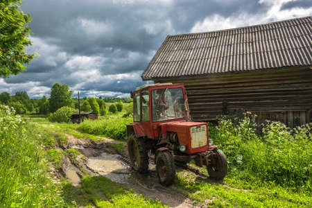 Wheel tractor on a country road in the summer cloudy day.の写真素材