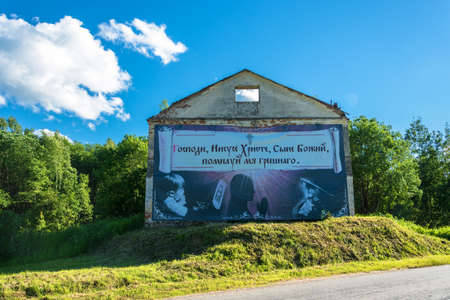 Dilapidated brick building with a large banner on the wall, standing beside the road.のeditorial素材