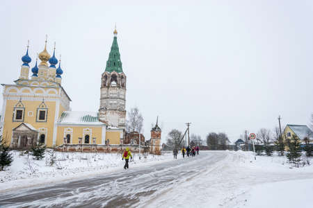 A group of tourists walking along the road in the village of Goritsy in the winter cloudy day, Ivanovo region, Russia.の写真素材