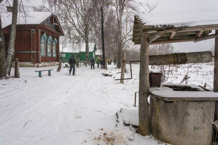 A small group of tourists is walking along the Russian village in a winter overcast day.の写真素材