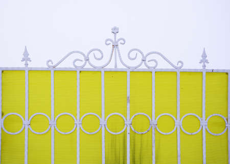 Beautiful curly white metal fence on a yellow striped background.の写真素材