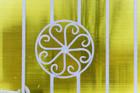 Beautiful curly white metal fence on a yellow striped background.の写真素材