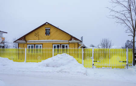 Village Vyatskoe, Yaroslavl region, Russia - February 17, 2018: A small wooden house with a bright yellow fence February 17, 2018 in the village of Vyatskoye, Yaroslavl region, Russia.のeditorial素材